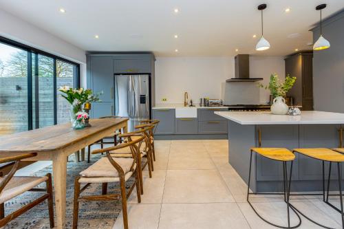 een keuken met een lange houten tafel en stoelen bij Stunning 5BR Home, SW London, 5 min Twickenham St in Twickenham