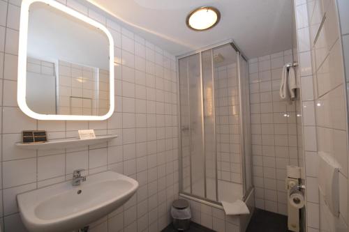 ein weißes Bad mit einem Waschbecken und einer Dusche in der Unterkunft Gästehaus Bavaria in Regensburg