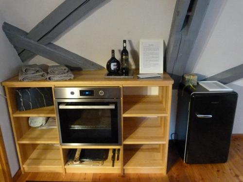 a wooden shelf with a microwave and a refrigerator at Maisonette-Appartment in historischem Ambiente in Iphofen