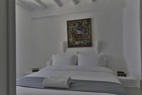 a bedroom with a white bed with a painting on the wall at Trieris Villa & Suites in Fira