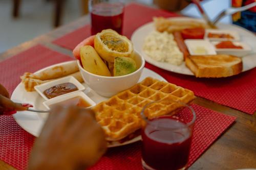 a table with a plate of waffles and a bowl of fruit at Shoki Shoki Hotel Stone Town in Zanzibar City