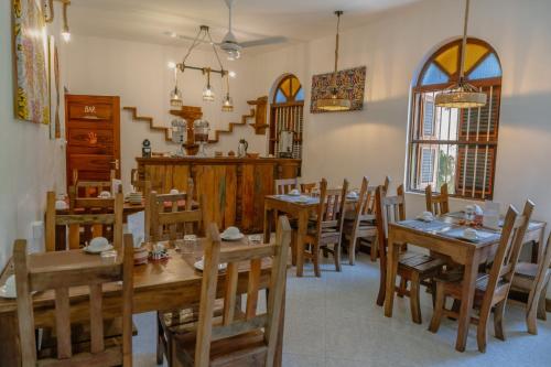 a dining room with wooden tables and chairs at Shoki Shoki House Stone Town in Zanzibar City
