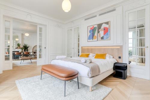 - une chambre blanche avec un grand lit et un tabouret dans l'établissement La Suite 31, à Paris