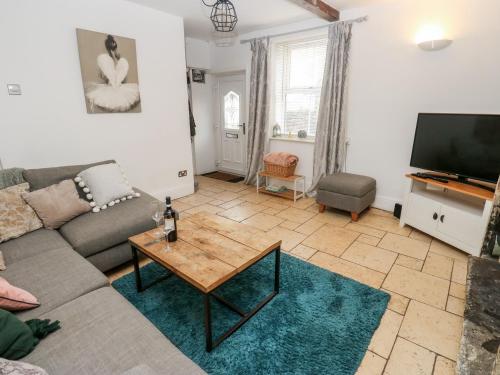 a living room with a couch and a tv at The Cottage in Yeadon