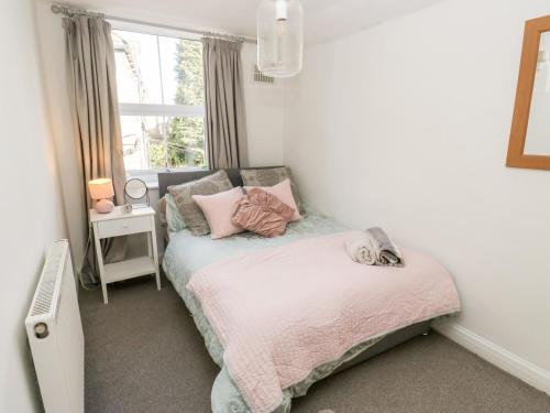 a small bedroom with a bed and a window at The Cottage in Yeadon