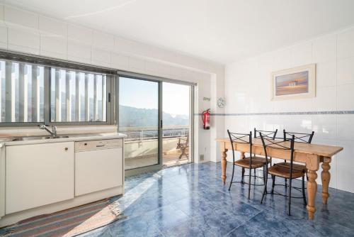 uma cozinha com mesa e cadeiras e uma janela em Homely Large Flat - Balcony em Guimarães