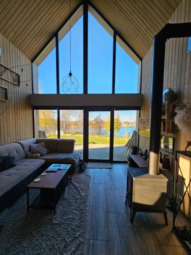 a living room with a couch and a large window at Hytte Na Wyspie -,,Roztoczańskie Morze'' in Kulików