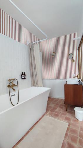 La salle de bains blanche est pourvue d'une baignoire et de toilettes. dans l'établissement Maison Charmeilles - La suite Fronsac, à Fronsac