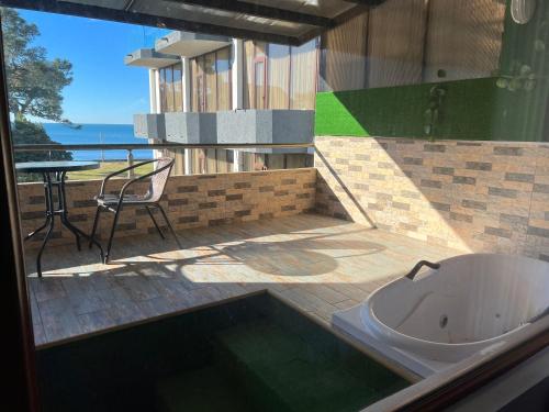 a bathroom with a tub and a patio with a table at KENT hotel & Restaurant KENT beach in K'obulet'i