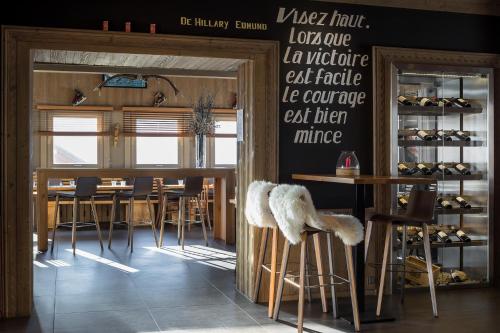 a restaurant with a bar with stools and a table at Hillary Hotel in Les Menuires