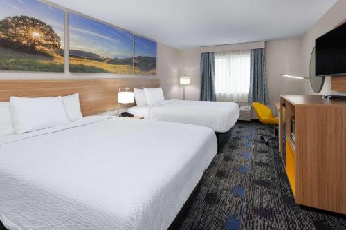 a hotel room with two beds and a flat screen tv at Days Inn by Wyndham Wooster in Wooster