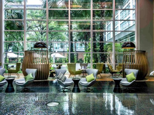 曼谷的住宿－曼谷鉑爾曼皇權酒店，大堂设有桌椅和大窗户。