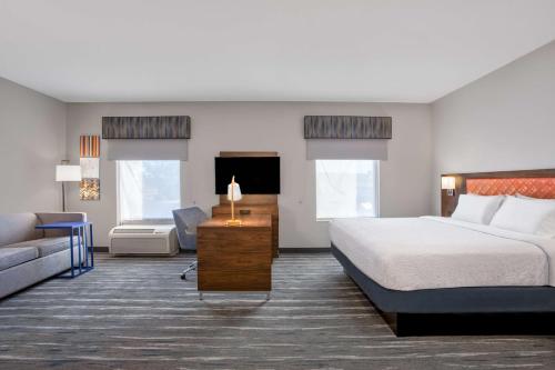 um quarto de hotel com uma cama e um sofá em Hampton Inn & Suites Muncie em Muncie