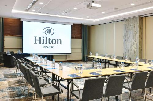 a conference room with tables and chairs and a screen at Hilton Gdansk in Gdańsk