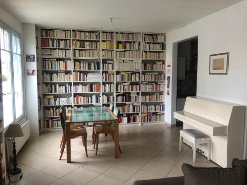 Cette chambre comprend une bibliothèque avec une table et un piano. dans l'établissement Maison village de Créteil, à Créteil