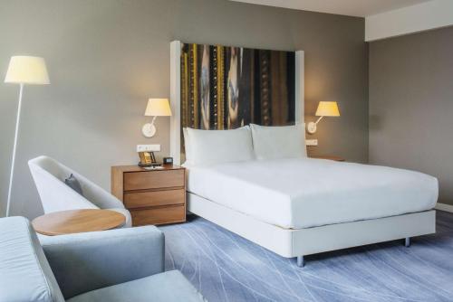 a bedroom with a large white bed and a chair at DoubleTree by Hilton Wroclaw in Wrocław