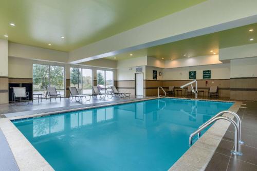 uma grande piscina num hotel com cadeiras e mesas em La Quinta by Wyndham Morgantown em Morgantown