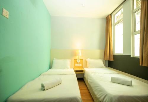 two beds in a room with two windows at JQ Station Eight Inn in Ipoh