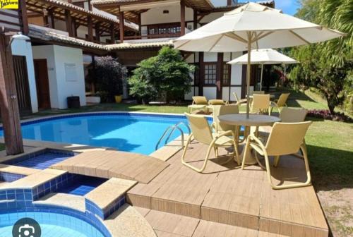 a patio with a table and umbrella next to a pool at Apartamento duplex em Praia do Forte - 2 suítes in Praia do Forte