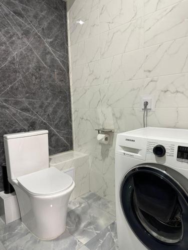 a bathroom with a washing machine and a toilet at Altai Apartments in Astana