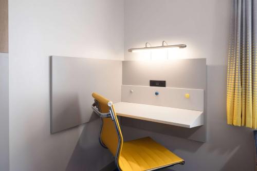 Camera con scrivania e sedia gialla. di Microtel Inn & Suites by Wyndham Macedon a Macedon