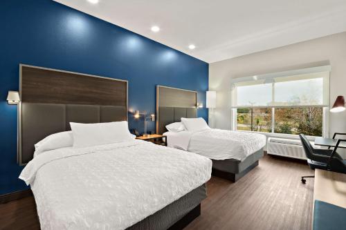 1 dormitorio con 2 camas y pared azul en Tru By Hilton Santee, en Santee