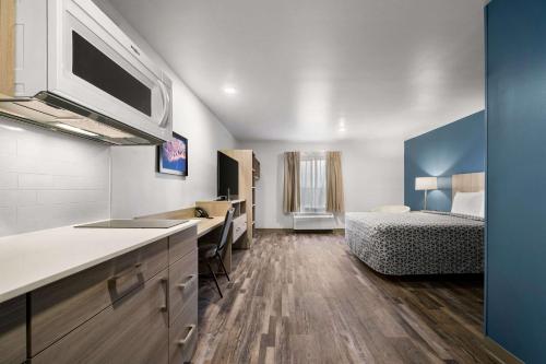 a room with a kitchen and a bedroom with a bed at WoodSpring Suites Dearborn Detroit in Dearborn