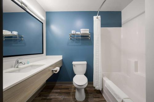 a bathroom with a toilet and a sink and a tub at WoodSpring Suites Dearborn Detroit in Dearborn