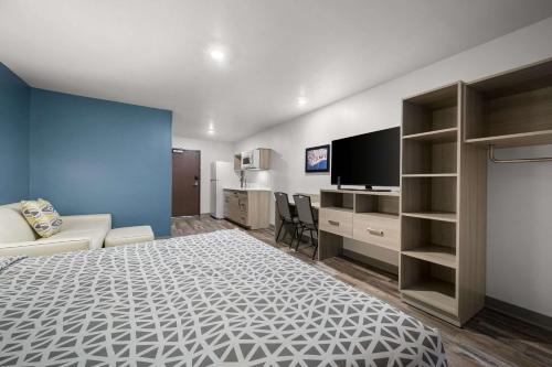 a bedroom with a bed and a tv and a couch at WoodSpring Suites Dearborn Detroit in Dearborn