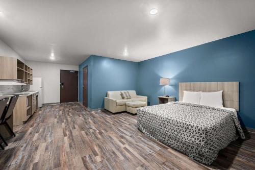 a bedroom with blue walls and a bed and a couch at WoodSpring Suites Dearborn Detroit in Dearborn