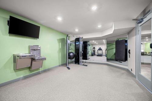 a gym with green walls and a flat screen tv at WoodSpring Suites Dearborn Detroit in Dearborn