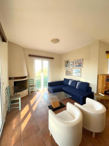 a living room with a blue couch and white chairs at Les Oliviers Villa with Sea view on Petani Beach in Vovikes