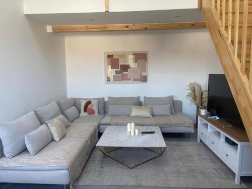 a living room with a couch and a tv at Grand Duplex Argenté 3 chambres à 20min de Paris in Argenteuil