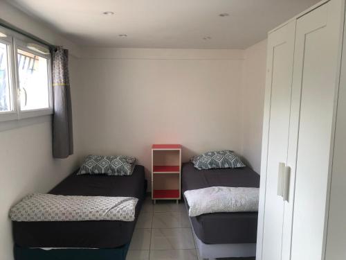 une petite chambre avec deux lits et une fenêtre dans l'établissement Appartement idéal ouvriers PAS DE TOURISME, à Stains