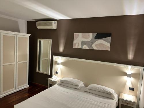 sypialnia z białym łóżkiem z 2 stolikami nocnymi i 2 lampami w obiekcie Inn Rome Rooms & Suites w Rzymie
