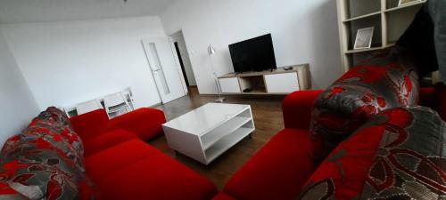 Stropkovにあるplne vybavený 3 izbový apartmánのリビングルーム(赤いソファ、テレビ付)