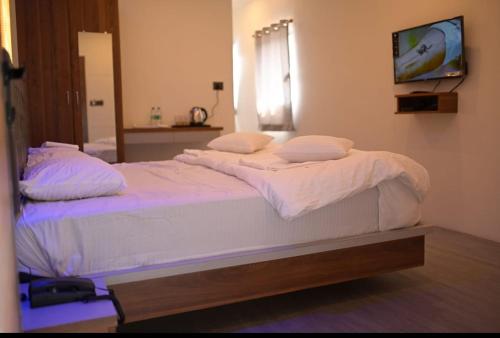 1 cama grande con sábanas blancas y almohadas en una habitación en Hotel Kapila Inn Ranjangaon, en Pune