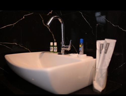 lavabo blanco con grifo en el baño en Hotel Kapila Inn Ranjangaon, en Pune