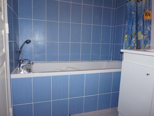 La salle de bains est pourvue de carrelage bleu, d'une baignoire et d'une douche. dans l'établissement Appartement 2 pièces avec piscine et parking privé, proche plage, Merville-Franceville-Plage - FR-1-465-26, à Merville-Franceville-Plage