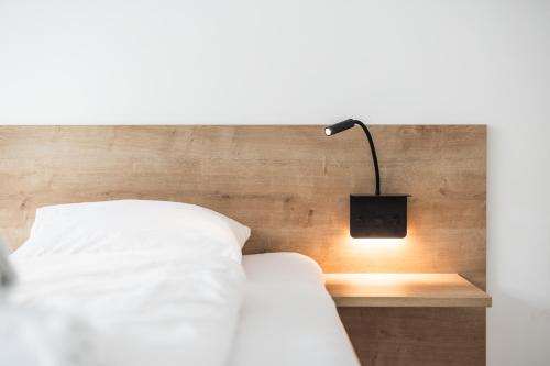 a bed with a lamp on a wooden headboard at myQuartier Central City Suites in Innsbruck