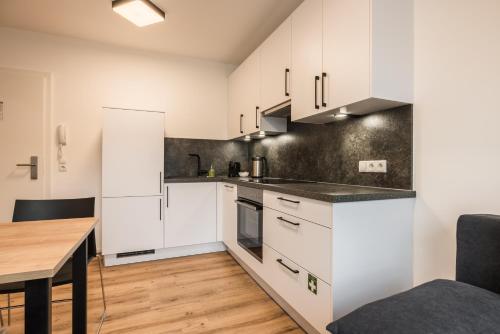 a kitchen with white cabinets and a wooden table at myQuartier Central City Suites in Innsbruck