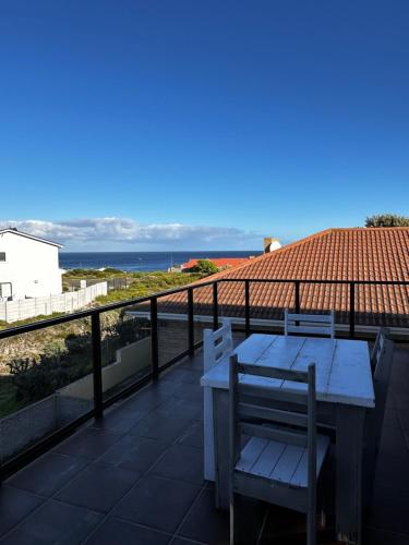 a table and chair on a balcony with a view of the ocean at Huisie by die See in Gansbaai