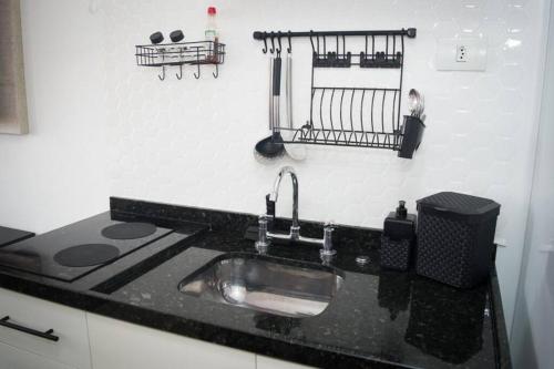 a kitchen with a sink and a black counter top at Apartamento ao Lado do metrô Carrão in Sao Paulo