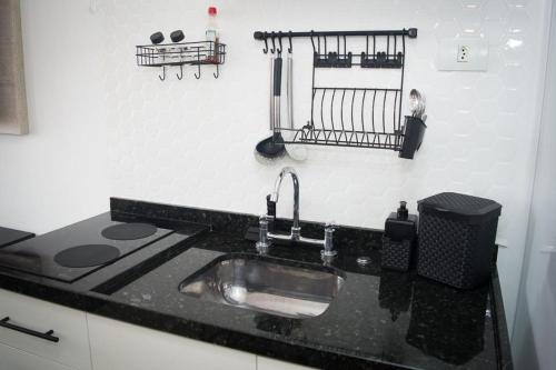 a kitchen sink with a black counter top at Apartamento ao Lado do metrô Carrão in Sao Paulo