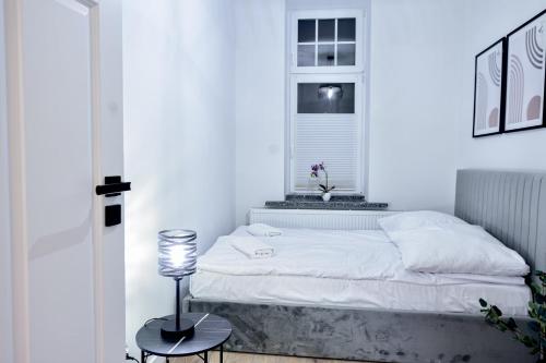 a white bedroom with a bed and a window at VacationClub - Old Town Apartament 12 in Kłodzko