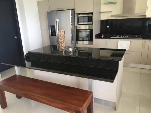 a kitchen with a black counter and a wooden bench at Vista Mar Relax in Mañanitas