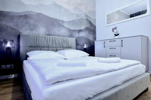 a bedroom with a large white bed with a painting on the wall at VacationClub - Old Town Apartament 11 in Kłodzko