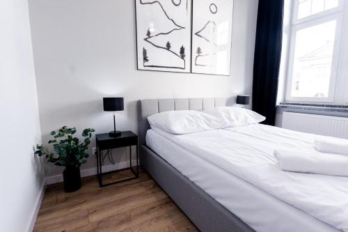 a bedroom with a white bed and a window at VacationClub - Old Town Apartament 9 in Kłodzko