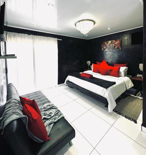 a bedroom with a large bed with red pillows at The Olive Branch Guesthouse and Animal Sanctuary in Upington