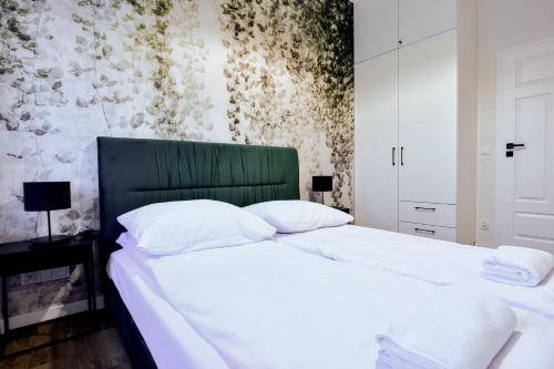 a bedroom with two white beds and a green headboard at VacationClub - Old Town Apartament 5 in Kłodzko